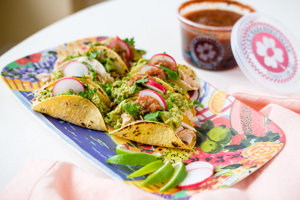 A plate of tacos with a container of Lucky Habanero salsa in the background.